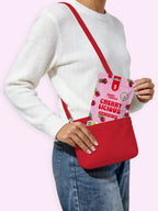 Person holding a red crossbody bag with a cherry-licious pouch on a pink background sugar free