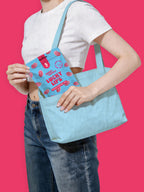 Person holding a blue tote bag with a small blue Lucky Lips pouch featuring pink text and graphics. sugar free