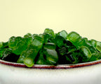 Green gummy dinosaurs in a bowl on a light yellow background sugar free