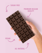 Chocolate bar held by a hand with 'sugar-free', 'premium Belgian quality', 'vegan', and 'all natural' text on a pink background.