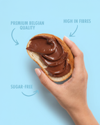 Hand holding a slice of bread with chocolate spread against a light blue background sugar free
