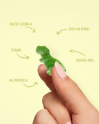 Green gummy dinosaur held by a hand with nutritional information on a yellow background  sugar free