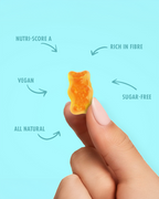 Hand holding a small orange gummy bear with nutritional information text on a light blue background sugar free