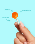 Hand holding a sugar-free lollipop with 'Vegan', 'All Natural', and 'Sugar-Free' text on a light blue background