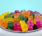 Colorful gummy bears in a white bowl with a light blue background sugar free