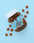Jar of 'Happy Hazelnut' spread with hazelnuts on a light blue background sugar free